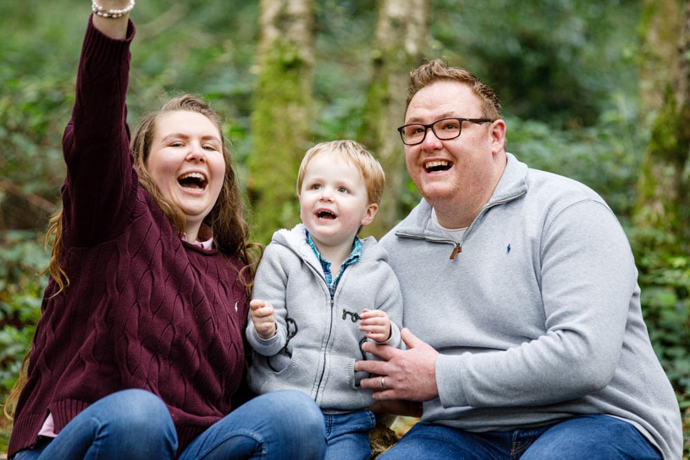 Family laughing whilst on a tree in the woods