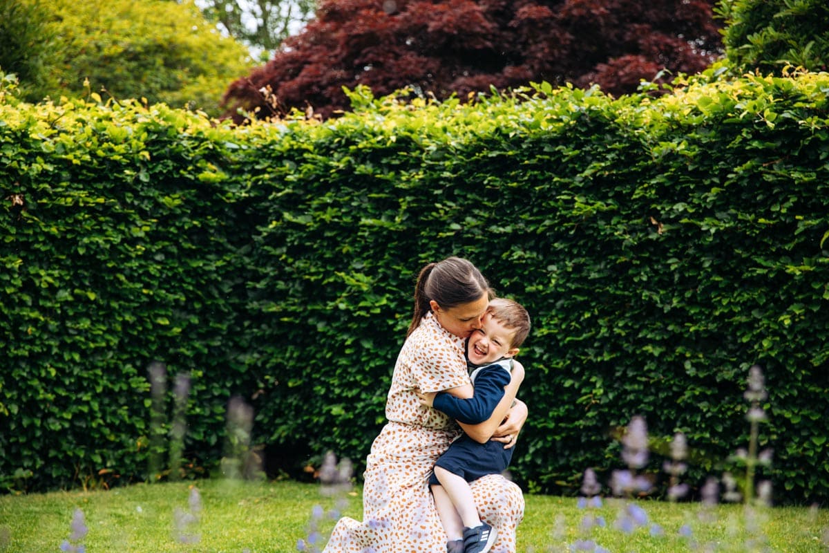 Mum cuddles son in garden