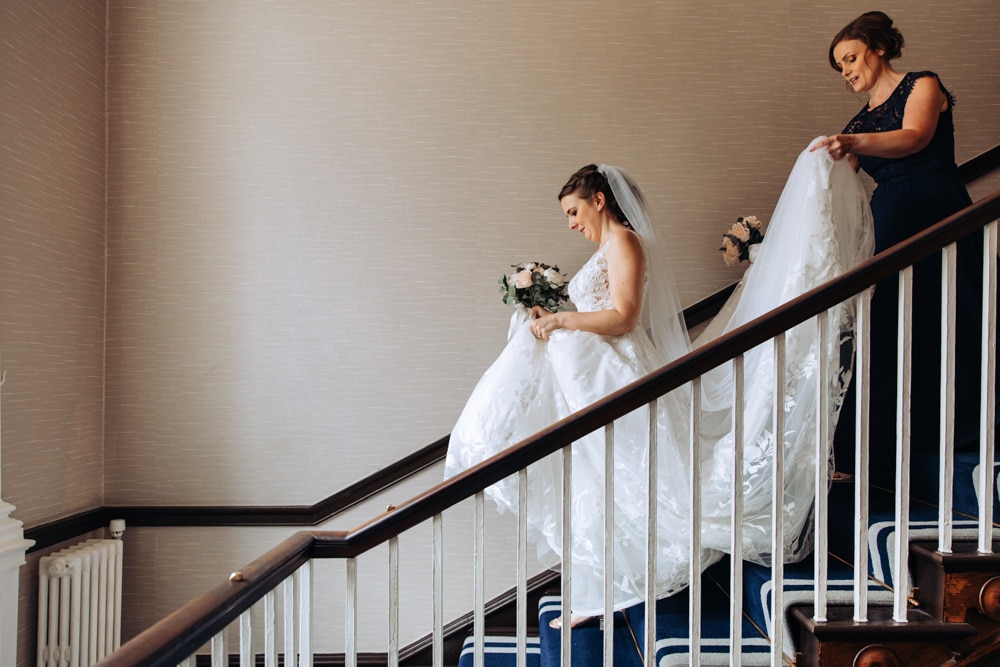 bride walking down staircase at mottram hall