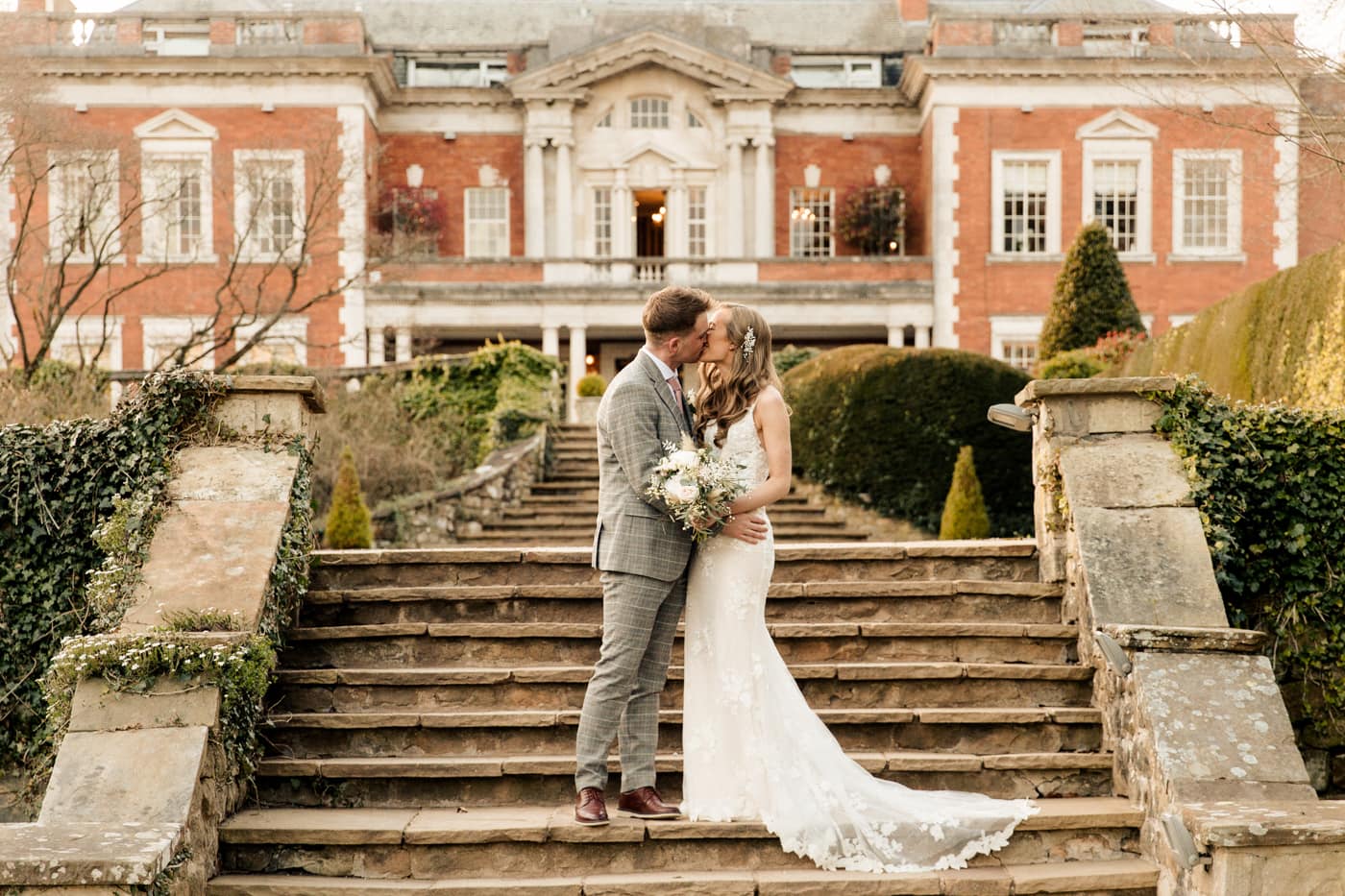 Lauren and patrick on the steps of eaves hall for their wedding portrait